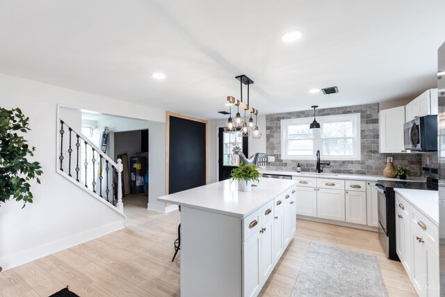 11475 Colthar Rd, Clark Twp, OH 45106 - kitchen with visible vents, a kitchen island, stainless steel microwave, light countertops, and black electric range oven