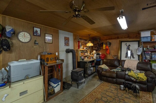 6651 Wizard Of Oz Way, Paint Twp, OH 45133 - living room with wood walls, concrete flooring, ceiling fan, and a wood stove