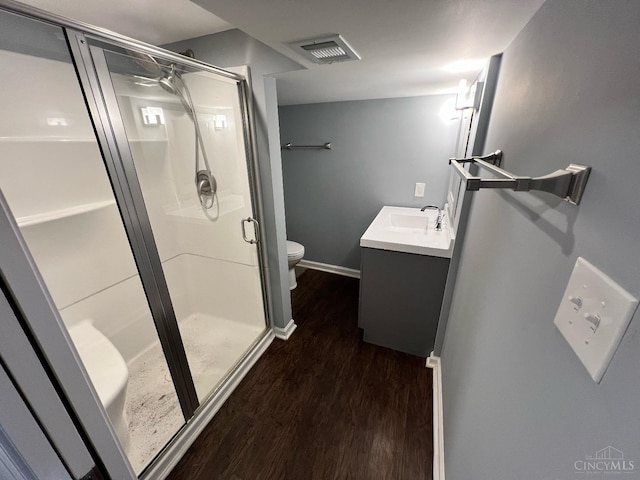 bathroom featuring visible vents, vanity, wood finished floors, toilet, and a shower stall