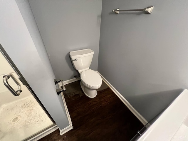 bathroom featuring baseboards, wood finished floors, and toilet