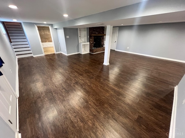 finished basement featuring baseboards, a brick fireplace, and wood finished floors