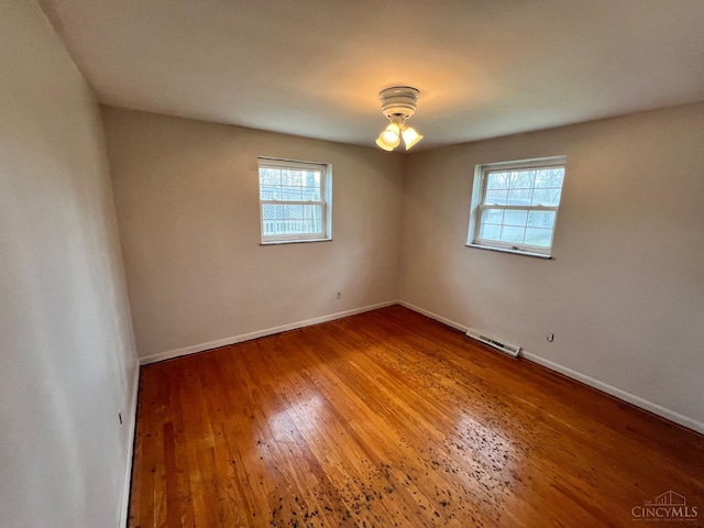 unfurnished room featuring visible vents, baseboards, plenty of natural light, and wood finished floors