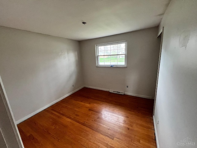 unfurnished room featuring baseboards, visible vents, and wood finished floors