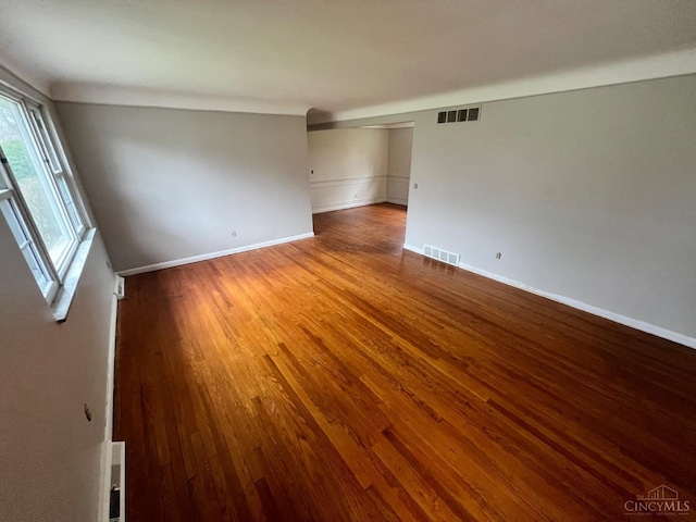 unfurnished room featuring baseboards, wood finished floors, and visible vents