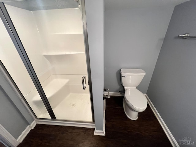 bathroom with baseboards, toilet, and a shower stall