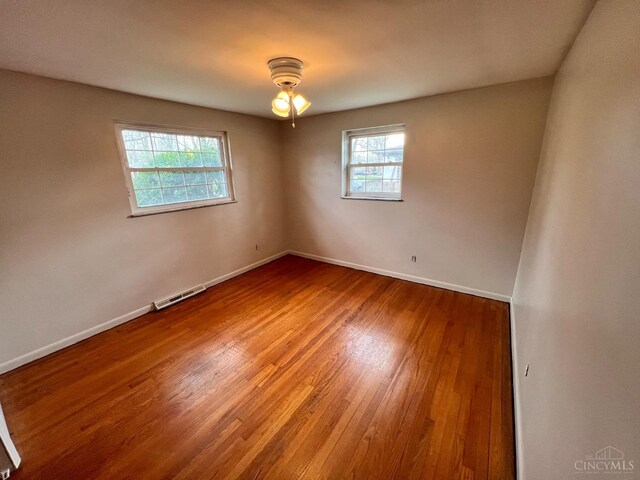 unfurnished room with baseboards, ceiling fan, wood finished floors, and visible vents