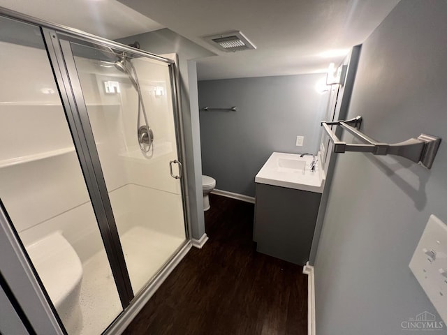 bathroom featuring visible vents, a shower stall, wood finished floors, vanity, and toilet