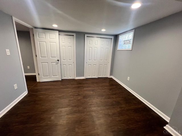 unfurnished bedroom with recessed lighting, baseboards, two closets, and dark wood-style floors