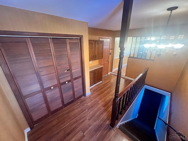 hallway with baseboards, dark wood finished floors, and an upstairs landing