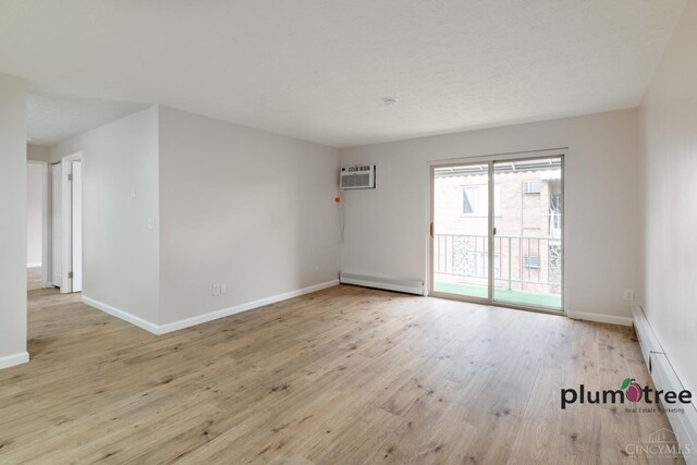 3640 Westwood Northern Blvd Unit 24, Cheviot, OH 45211 - unfurnished room with light wood-style flooring, a baseboard radiator, a wall mounted AC, and baseboards