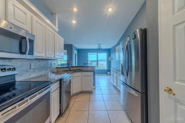 10701 Stone Ridge Way, Harrison, OH 45030 - kitchen featuring a sink, decorative backsplash, white cabinets, a peninsula, and appliances with stainless steel finishes