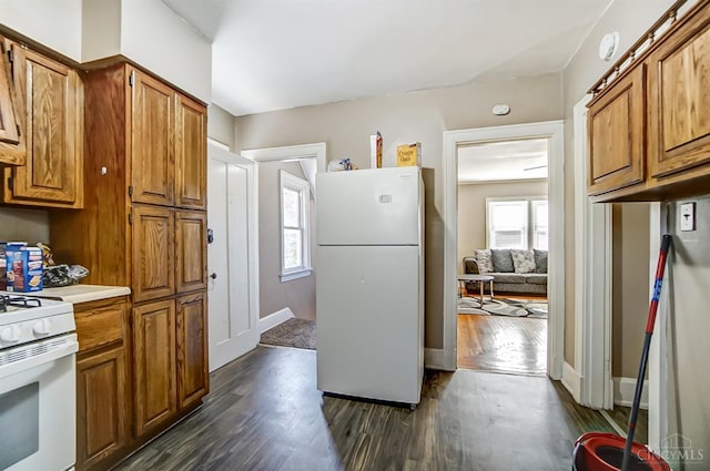 kitchen with brown cabinets, dark wood finished floors, light countertops, and white appliances