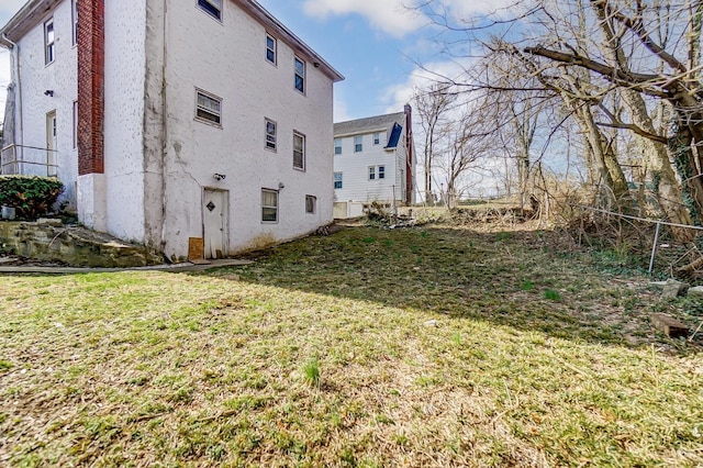 view of property exterior featuring a yard, stucco siding, and fence