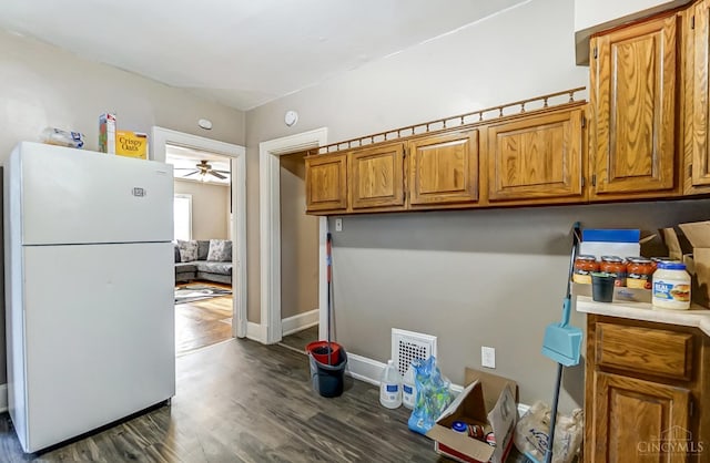 kitchen featuring brown cabinets, light countertops, dark wood-type flooring, visible vents, and freestanding refrigerator