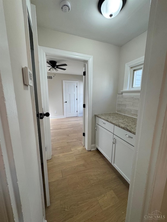 corridor featuring light wood-type flooring, baseboards, and visible vents