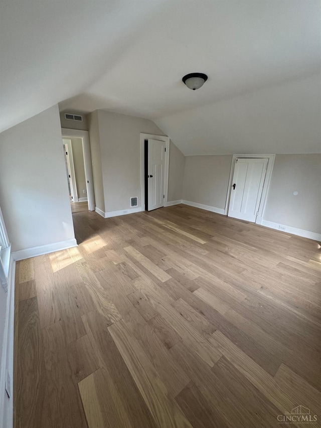 bonus room with vaulted ceiling, wood finished floors, visible vents, and baseboards