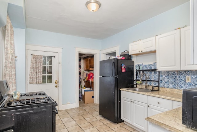 kitchen with white cabinets, light tile patterned floors, a sink, and black appliances