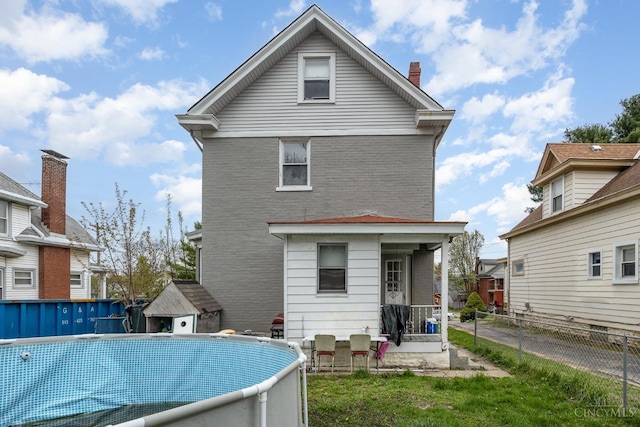 rear view of property featuring a chimney, a yard, a fenced in pool, and fence private yard