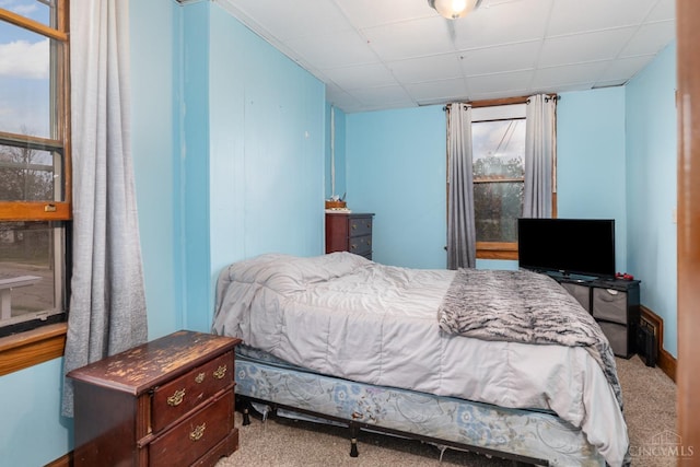 carpeted bedroom featuring a drop ceiling