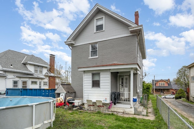 back of house featuring a yard, fence private yard, a fenced in pool, and a chimney