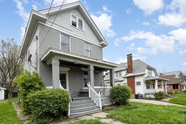 traditional style home with a porch, a front lawn, brick siding, and central AC unit