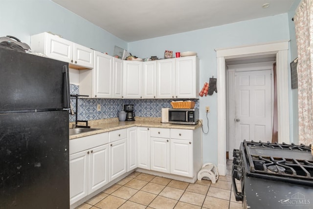 kitchen featuring black appliances, light tile patterned floors, light countertops, backsplash, and white cabinetry