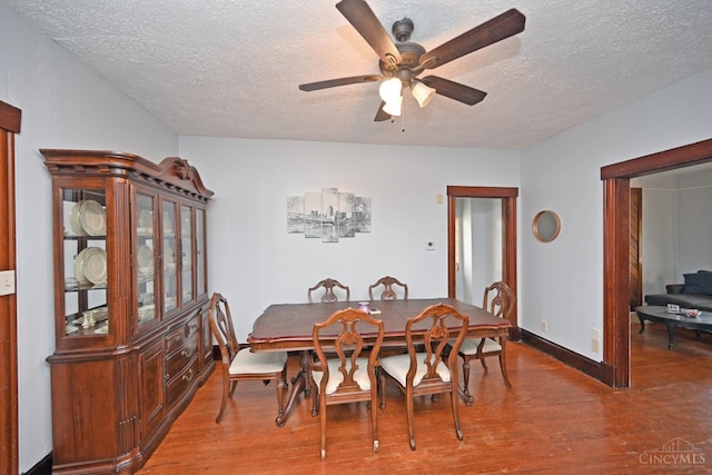 dining room with ceiling fan, baseboards, wood finished floors, and a textured ceiling