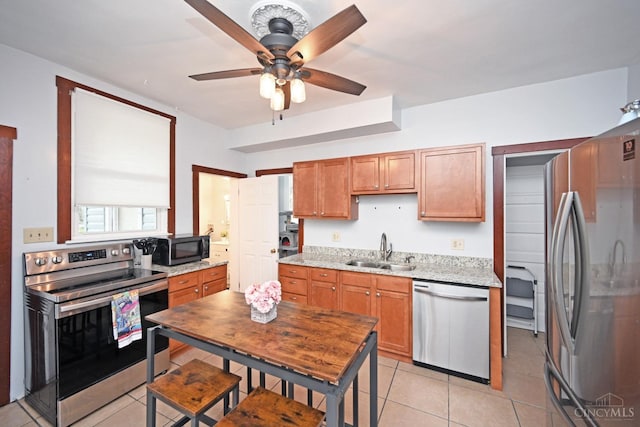 kitchen featuring a sink, light tile patterned flooring, a ceiling fan, light stone counters, and appliances with stainless steel finishes
