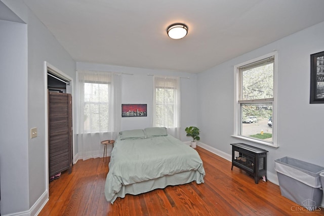 bedroom featuring wood finished floors, baseboards, and multiple windows