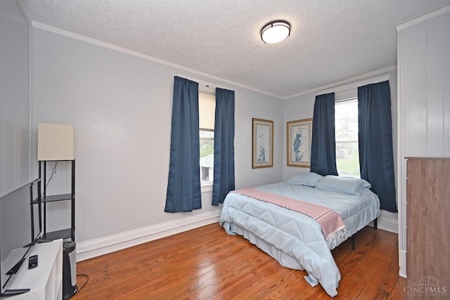 bedroom with hardwood / wood-style floors, a textured ceiling, baseboards, and ornamental molding