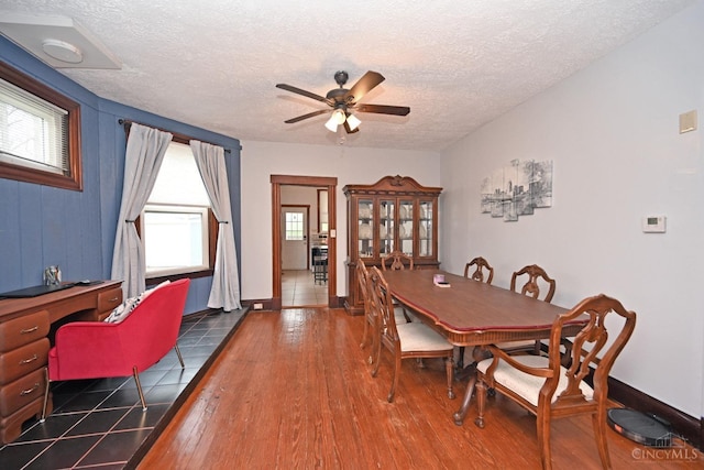 dining area featuring wood-type flooring, a ceiling fan, and a textured ceiling