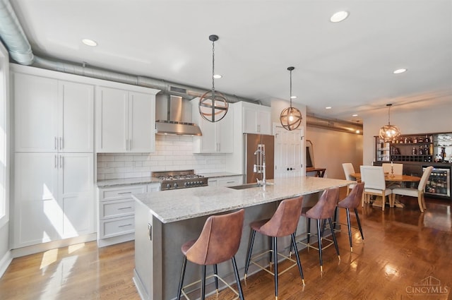 1308 Broadway St Unit 2, Cincinnati, OH 45202 - kitchen featuring wall chimney range hood, range, a sink, a kitchen island with sink, and tasteful backsplash