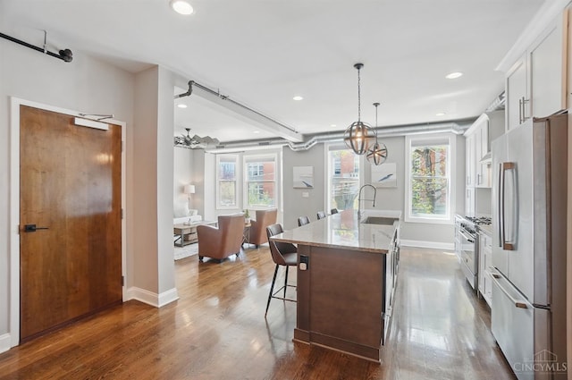 1308 Broadway St Unit 2, Cincinnati, OH 45202 - kitchen with refrigerator, high end stainless steel range oven, a sink, white cabinetry, and a center island with sink