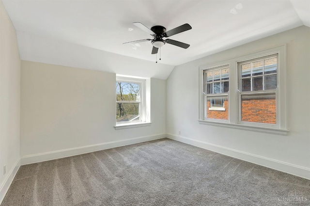 spare room with vaulted ceiling, a ceiling fan, carpet flooring, and baseboards