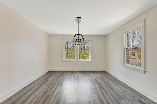 unfurnished dining area featuring plenty of natural light, wood finished floors, and a notable chandelier
