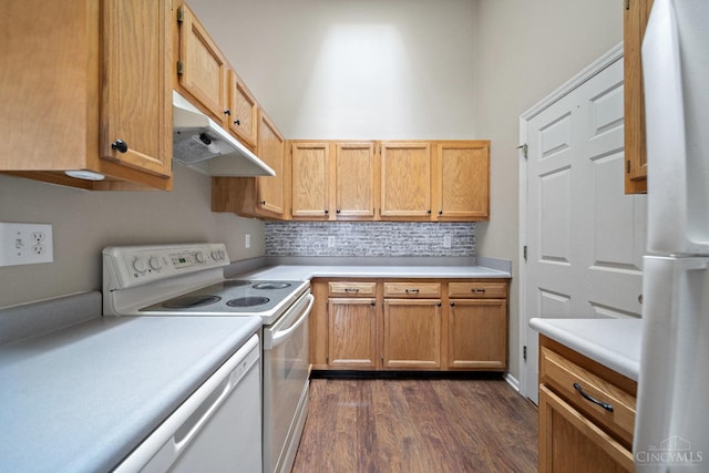 kitchen with dark wood-style floors, under cabinet range hood, light countertops, backsplash, and white appliances