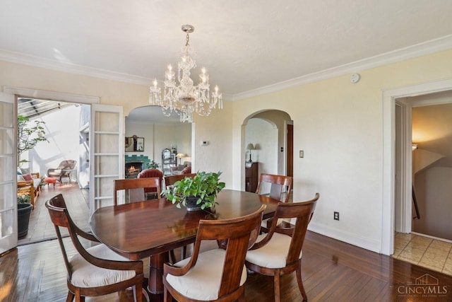 3725 Dogwood Ln, Columbia Twp, OH 45213 - dining area featuring arched walkways, wood finished floors, ornamental molding, a chandelier, and a lit fireplace
