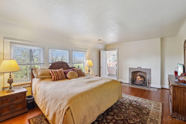 3725 Dogwood Ln, Columbia Twp, OH 45213 - bedroom with wood finished floors, a tiled fireplace, a textured ceiling, and ensuite bath