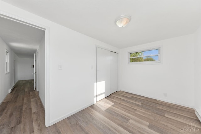 unfurnished bedroom with a closet, wood finished floors, and baseboards