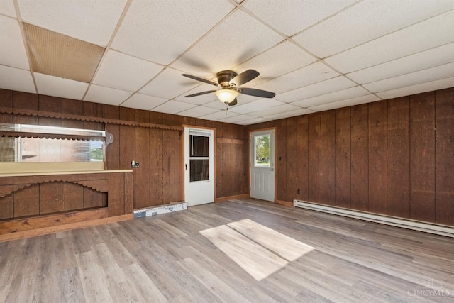spare room featuring wood walls, wood finished floors, a ceiling fan, and a paneled ceiling