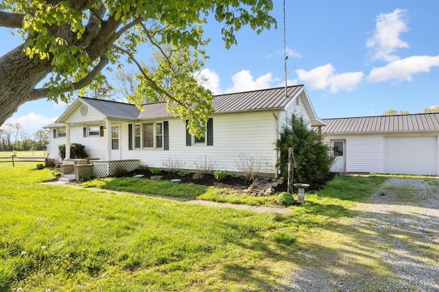 view of front of home with a front yard, metal roof, gravel driveway, and an attached garage