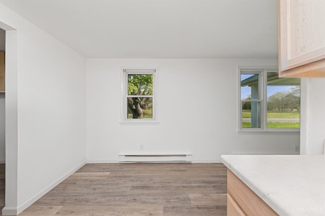 interior space with a baseboard radiator, light wood-style flooring, and baseboards