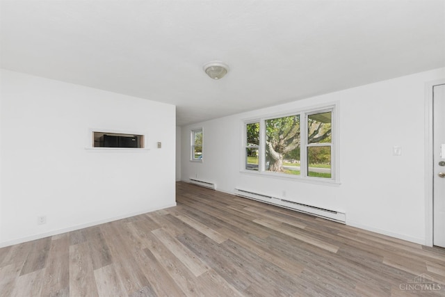 empty room with a baseboard radiator, wood finished floors, a baseboard heating unit, and baseboards