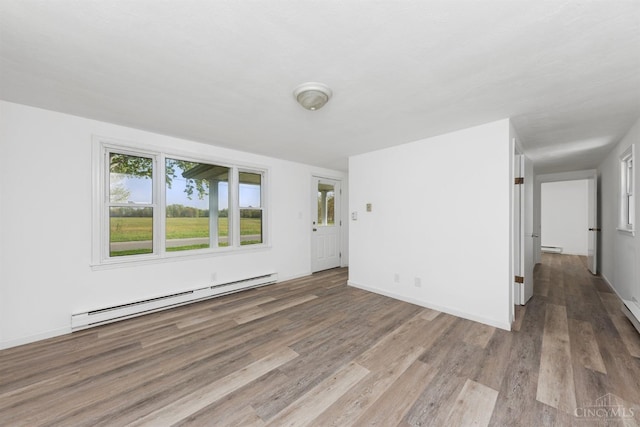 unfurnished living room with a baseboard radiator, wood finished floors, a baseboard heating unit, and baseboards