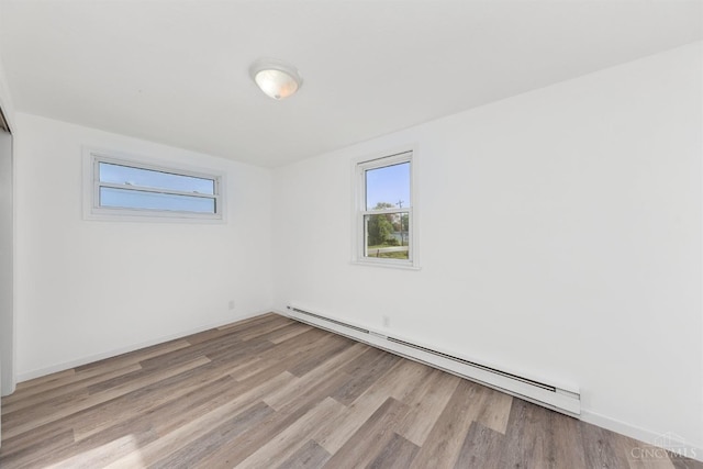unfurnished room featuring wood finished floors and a baseboard radiator