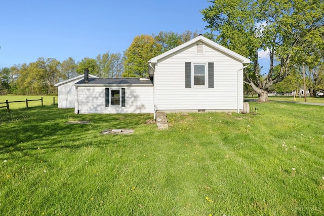 back of house featuring fence, a yard, and crawl space
