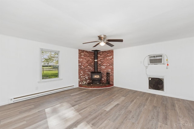 unfurnished living room with a baseboard radiator, wood finished floors, a wall unit AC, and a wood stove