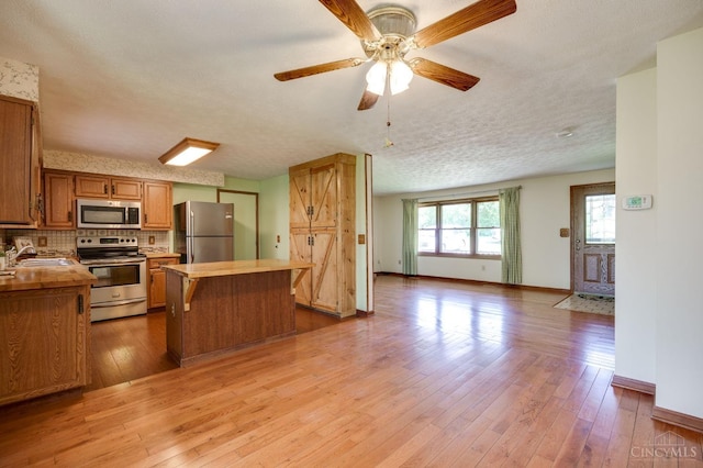 6139 N State Route 48, Clearcreek Twp, OH 45036 - kitchen with appliances with stainless steel finishes, open floor plan, a center island, light wood-type flooring, and decorative backsplash