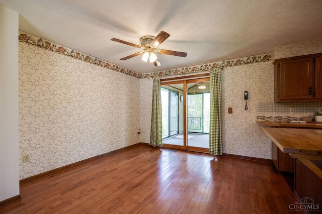 6139 N State Route 48, Clearcreek Twp, OH 45036 - unfurnished dining area with wallpapered walls, hardwood / wood-style flooring, a ceiling fan, baseboards, and a textured ceiling