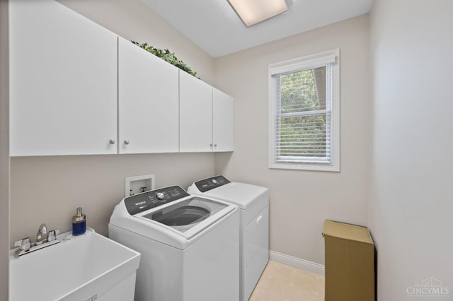 laundry room featuring cabinet space, a sink, baseboards, light tile patterned floors, and washer and clothes dryer